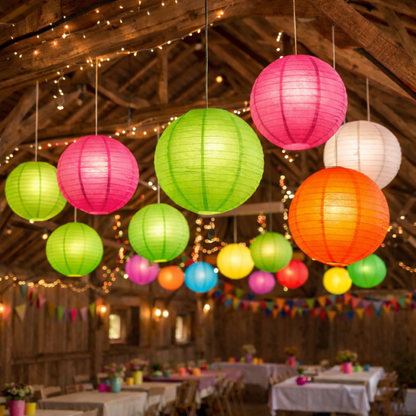 Colorful paper lanterns hanging in a rustic barn with tables and decorations.