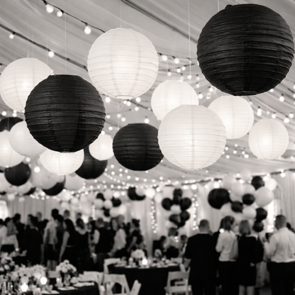 Black and white paper lanterns hanging in a tent with people and tables below.