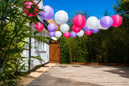 16-inch Lilac, Fuchsia and White nylon lanterns for a summer garden gathering. Hung across the space using fairy lights.